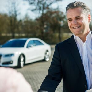 Geschäftsführer im Gespräch vor Fahrzeug